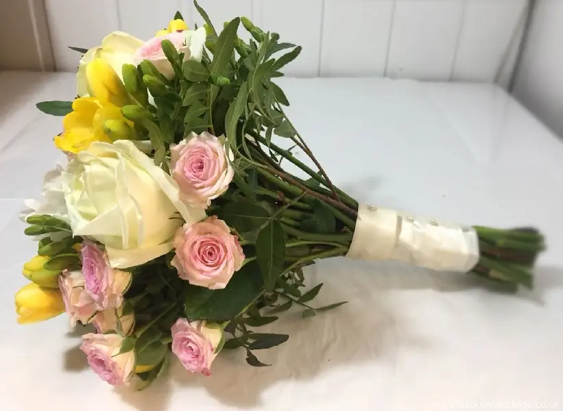 Bridesmaid hand-tied bouquet of spring flowers including roses, spray roses, ranunculus, freesia and narcisis