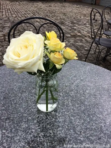 Wedding venue table centerpiece of rose and spray roses in jars