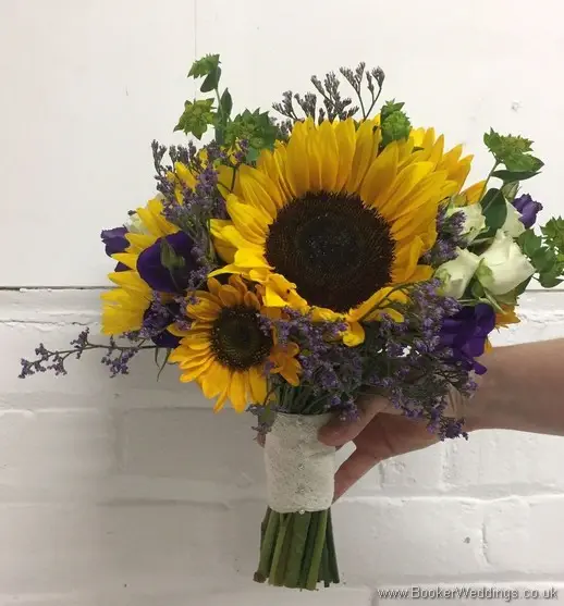 Bridal handtied bouquet with sunflowers, yellow gerberas, white spray roses, purple limoneum and purple lissianthus side view