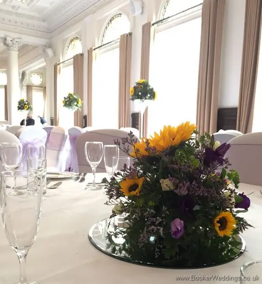 Low posy arrangements on mirror plate with sunflowers, yellow gerberas, white spray roses, purple lissianthus at Doubletree by Hilton Liverpool