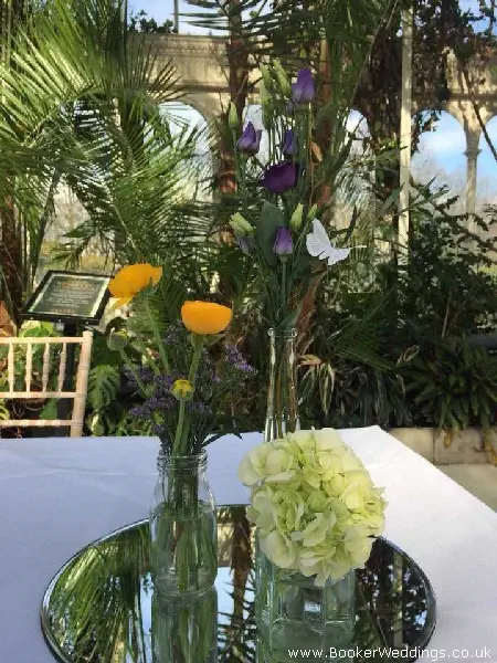 Table centrepiece of three jars with bright wedding flowers